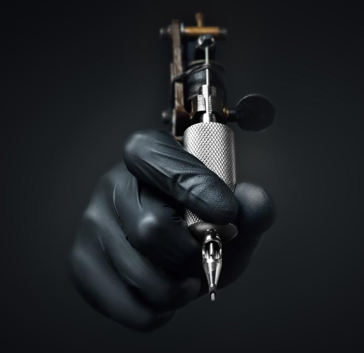 black gloved hand holding a tattoo machine